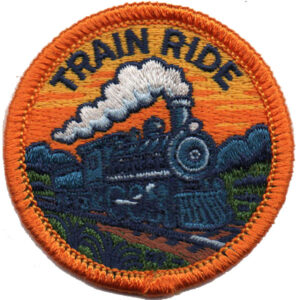 The Train Ride Patch is a round embroidered patch with an orange border, showing a steam train on tracks and "TRAIN RIDE" at the top against an orange sunset and dark blue-green landscape.