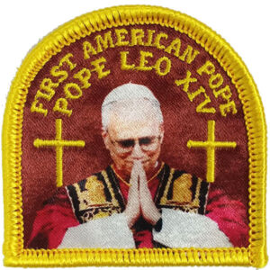 The First American Pope Patch features “First American Pope Pope Leo XIV” in yellow text above a white-haired, glasses-wearing pope with hands in prayer, flanked by two crosses and bordered in yellow embroidery.