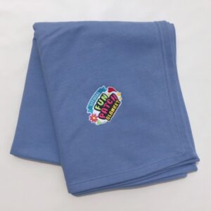 A folded Carolina Blue Patch Blanket featuring a colorful embroidered center patch with playful fonts and flower designs that reads "Virtual Fun Ranch Blanket.