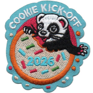 An embroidered patch features a black and white ferret peeking over a bitten, sprinkle-covered cookie with "2026" on it. The words "COOKIE KICK-OFF" are stitched above on a blue scalloped background.