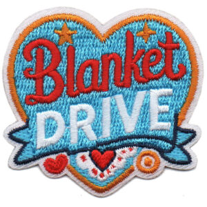 The Blanket Drive Patch (Copy) is a colorful embroidered heart-shaped patch with stars, hearts, and patterns, featuring "Blanket DRIVE" in bold red and white letters on a blue background.