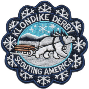 The Klondike Derby Bear Patch features a polar bear pulling a sled in a snowy mountain landscape with snowflakes and the text "Klondike Derby, Scouting America.
