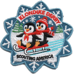 Embroidered patch featuring two bears on a sled in red scarves and hats, surrounded by snowflakes, trees, and the text "KLONDIKE DERBY" and "SCOUTING AMERICA." Product: Klondike Derby Bear Patch (Copy).