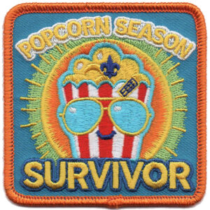 The Popcorn Season Survivor Patch features a popcorn bucket with sunglasses and a bandage, sun rays, “POPCORN SEASON SURVIVOR” text, a blue background, and an orange border.