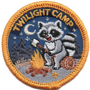 The Twilight Camp Patch (Copy) is a round embroidered patch with a gold border, featuring a raccoon roasting a marshmallow over a campfire beneath stars, pine trees, and a crescent moon, with "TWILIGHT CAMP" at the top.