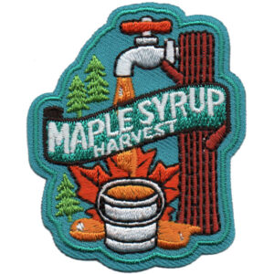 The Maple Syrup Harvest Patch (Copy) features an embroidered tree tapped for syrup, a bucket, green pine trees, an orange maple leaf, and "MAPLE SYRUP HARVEST" in white text.