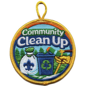 A round embroidered Trail Cleanup (Copy) patch with a yellow border features "Community Clean Up" above images of a recycling bin, trash bag, rake, gloves, trees, and blue sky.