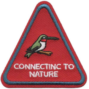 A red triangle patch with a blue border shows an embroidered bird on a branch above the white “Connecting to Nature” text.