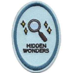 The Just Imagine Patch (Copy) features a magnifying glass and four yellow stars above "HIDDEN WONDERS" on a light blue oval background, outlined by a darker blue border.
